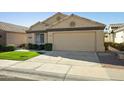 Tan house with a two-car garage and well-maintained lawn at 14535 W Zuni Trl, Surprise, AZ 85374