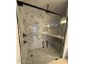 Luxurious bathroom showcasing a frameless glass shower with marble tiling and mosaic flooring at 16994 W Canterbury Dr, Surprise, AZ 85388