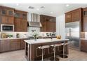 A modern kitchen featuring wooden cabinetry, stainless steel appliances, and a white countertop island with barstool seating at 16994 W Canterbury Dr, Surprise, AZ 85388