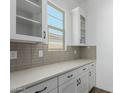Beautiful kitchen with white cabinets, light countertops, stylish backsplash, and a window for natural light at 11950 W Parkway Ln, Avondale, AZ 85323