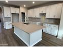 Spacious kitchen with white cabinets, herringbone backsplash, and large island at 9987 W Verde Ln, Avondale, AZ 85392