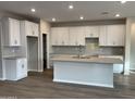 Modern kitchen featuring white cabinets, a large island, and herringbone backsplash at 9987 W Verde Ln, Avondale, AZ 85392