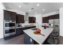 Modern kitchen boasts stainless steel appliances, dark wood cabinets, and a large center island with white countertop at 8722 W Denton Ln, Glendale, AZ 85305