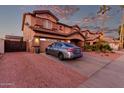 Side view of a two-story home with desert landscaping, a two-car garage, and a long driveway at 14244 W Indianola Ave, Goodyear, AZ 85395