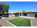 Spacious backyard featuring an artificial lawn, patio with furniture, grill, and gravel area at 1531 W Plana Ave, Mesa, AZ 85202