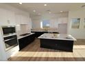 Bright kitchen features white cabinets, stainless appliances, and an island with a white countertop at 32535 N 135Th Dr, Peoria, AZ 85383