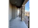 Inviting covered front porch adorned with stone pillars and a neutral color palette at 10015 W Verde Ln, Avondale, AZ 85392