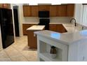 Bright kitchen with island features wood cabinetry, granite counters, black appliances, and breakfast bar with decorative shelving at 19661 N Echo Rim Dr, Surprise, AZ 85387