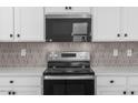 Well-equipped kitchen with stainless steel appliances, tiled backsplash, and modern white cabinetry at 18180 W Pima St, Goodyear, AZ 85338