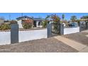 Curb view of home with block fence, wrought iron gate, and rose bushes at 2124 W Maricopa St, Phoenix, AZ 85009