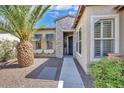 Inviting single-Gathering home featuring a charming front entrance with stone accents and a palm tree at 13055 W Eagle Talon Trl, Peoria, AZ 85383