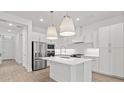 Modern white kitchen with stainless steel appliances, a kitchen island, stylish pendant lighting, and light wood flooring at 20306 W Turney Ave, Buckeye, AZ 85396