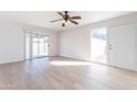 Bright living room with light wood-look floors, neutral walls, a ceiling fan, and sliding glass doors at 7508 W Osborn Rd, Phoenix, AZ 85033