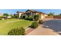 Spacious single-story home with a well-manicured lawn and paver driveway leading to the garage at 19575 E Vallejo St, Queen Creek, AZ 85142