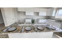 Modern kitchen features granite countertops, white cabinets and is staged with place settings for a formal dinner at 3810 N Mateo Dr, Eloy, AZ 85131