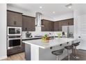 Modern kitchen featuring stainless steel appliances, dark wood cabinets and a large white quartz island with seating at 14189 W Sand Hills Rd, Surprise, AZ 85387