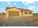 A single-story tan home with a brown roof, brown shutters, and a two-car garage under a cloudy blue sky at 31824 N 221St Dr, Wittmann, AZ 85361