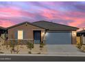 Single story home with gray garage door, beautiful sunset in the background at 22502 W Tonopah Dr, Surprise, AZ 85387