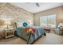 Comfortable bedroom featuring a stone accent wall, neutral colors, and a cozy window nook at 2425 W Bronco Butte Trl # 1002, Phoenix, AZ 85085