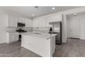 Bright kitchen featuring white cabinetry, stainless steel appliances, a kitchen island, and grey wood-look floors at 12333 W Marguerite Ave, Avondale, AZ 85323
