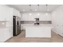 A modern kitchen showcases white cabinets, stainless steel appliances, and a central island, all beneath pendant lights at 5338 W Manzanita Dr, Glendale, AZ 85302