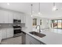 Well-lit kitchen with a large island, white cabinets, stainless steel appliances and a view to the great room at 5344 W Manzanita Dr, Glendale, AZ 85302