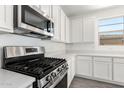 Close-up of the gourmet kitchen with stainless steel gas range, microwave, and white cabinets at 12326 W Marguerite Ave, Avondale, AZ 85323
