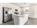 Bright kitchen featuring sleek white cabinetry, stainless steel appliances, and a large island with quartz countertops at 12326 W Marguerite Ave, Avondale, AZ 85323