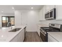 View of modern kitchen island, stainless appliances, white cabinets and stylish wood-look tile flooring at 12330 W Marguerite Ave, Avondale, AZ 85323