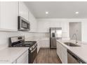 Open kitchen boasts stainless steel appliances, white cabinets, countertops, and island for modern living at 12330 W Marguerite Ave, Avondale, AZ 85323