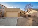 Tan one-story house with a two-car garage and mature trees at 1952 N 103Rd Dr, Avondale, AZ 85392