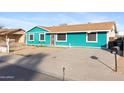 View of the teal home, showcasing the driveway and simple desert landscaping at 323 N 69Th Ave, Phoenix, AZ 85043