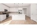 Bright kitchen boasts white cabinetry, stainless steel appliances, and a large center island with pendant lighting at 5335 W Manzanita Dr, Glendale, AZ 85302