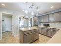 Stylish kitchen with gray cabinetry, stainless steel oven, tile backsplash, and a center island at 34 N Agua Fria Ln, Casa Grande, AZ 85194