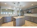 Spacious kitchen featuring gray cabinets, stainless steel appliances, tile backsplash, and central island at 34 N Agua Fria Ln, Casa Grande, AZ 85194