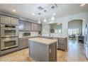 Well-appointed kitchen with gray cabinets, stainless steel appliances, tile backsplash and center island at 34 N Agua Fria Ln, Casa Grande, AZ 85194