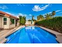 A backyard pool features sparkling blue water and is surrounded by mature landscaping and privacy hedges at 11035 E Clinton St, Scottsdale, AZ 85259