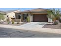 Tan house with brown garage door and landscaping at 14133 S 179Th Ave, Goodyear, AZ 85338