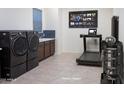 Modern laundry room with front loading washer and dryer, sink, weights, and a treadmill for exercising while you wash at 14133 S 179Th Ave, Goodyear, AZ 85338