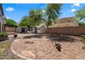 Large brick-paved backyard featuring mature trees, sheds, and ample space for entertaining and outdoor activities at 12943 W Mclellan Rd, Glendale, AZ 85307