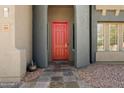 Charming front entrance showcasing a vibrant red door, stone tile walkway, and meticulously maintained landscaping at 12943 W Mclellan Rd, Glendale, AZ 85307