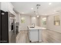Open kitchen with stainless steel appliances, a center island, and wood-look flooring at 2888 N Evergreen St, Buckeye, AZ 85396