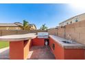 Outdoor kitchen featuring a built-in grill, bar seating, and sink, perfect for outdoor entertaining at 272 N 167Th Ln, Goodyear, AZ 85338