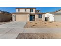 Two-story house with tan exterior, teal door, and landscaped yard at 18424 W Monte Lindo Ln, Surprise, AZ 85387