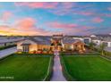 Aerial view showcasing a home's landscaped front yard, pristine lawn, and charming architectural details against a colorful sunset at 2652 E Pelican Ct, Gilbert, AZ 85297