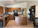 Well-equipped kitchen features ample wooden cabinetry, a functional island, and stainless steel appliances at 12009 W Aster Dr, El Mirage, AZ 85335