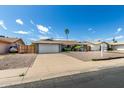 Lovely single-story home showcasing a two-car garage, desert landscaping, and a cozy seating area in the front yard at 3425 W Acoma Dr, Phoenix, AZ 85053