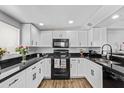 Modern kitchen featuring white cabinets, stainless steel appliances, and black countertops at 728 W Grove Cir, Mesa, AZ 85210