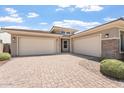 Expansive three-car garage with brick accents, complemented by mature landscaping in front of home at 28389 N 131St Dr, Peoria, AZ 85383