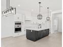 Modern kitchen features white cabinets, stainless steel appliances, and an island with black cabinets at 18083 W Amber Dr, Goodyear, AZ 85338